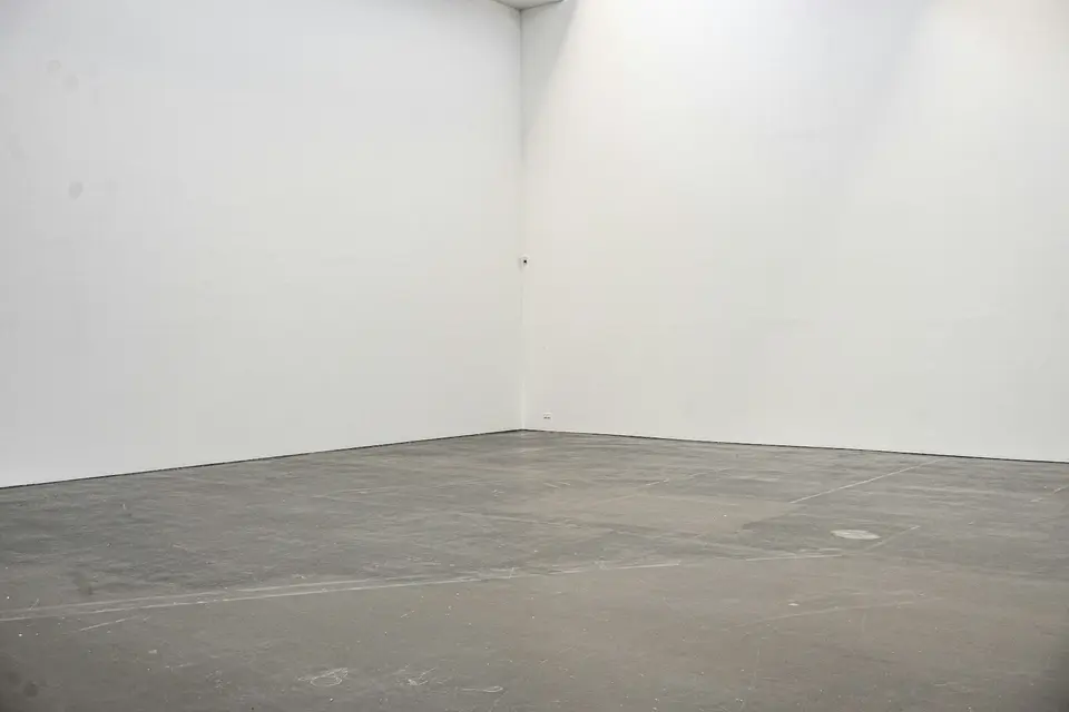 Een lege ruimte met witte wanden en een kale betonvloer, nog zonder afwerking